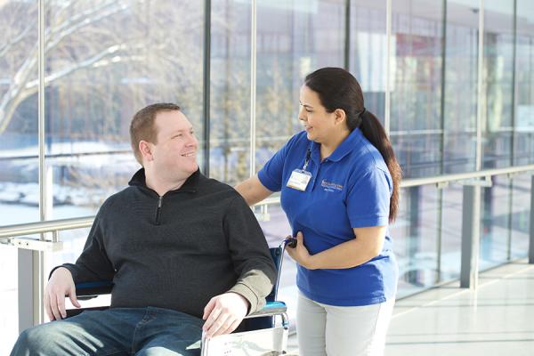 Guest service transporting patient in wheelchair